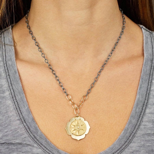 Lulu Designs Eclipse Necklace - Available at Shaylula Jewlery & Gifts in Tarrytown, NY and online. The shadows, light, and layers of a celestial event embodied by Eclipse. A yellow bronze charm featuring starburst beading and diamond swings atop the backdrop of an open lotus pendant on a 14k gold filled oval link chain. Made with love in Mill Valley, CA. (model is wearing mix metal) • Diamond, yellow bronze, 14k gold filled• 18" L • Lobster clasp