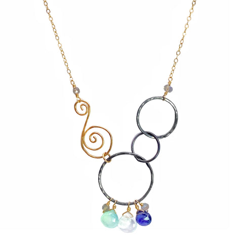 Vannucci Mixed Metal Circle Swirl Necklace - Available at Shaylula Jewlery & Gifts in Tarrytown, NY and online. This mixed metal necklace is whimsical, artsy and perfect for everyday! The hammered details are accented with chubby briolettes of chalcedony, moonstone and iolite. A handcrafted tension "S" clasp closure is perfect for anyone that struggles with a lobster clasp. It's hip to be square! • Chalcedony, moonstone, iolite, oxidized sterling silver, 14k gold filled • 16" L • Tension "S" clasp closure