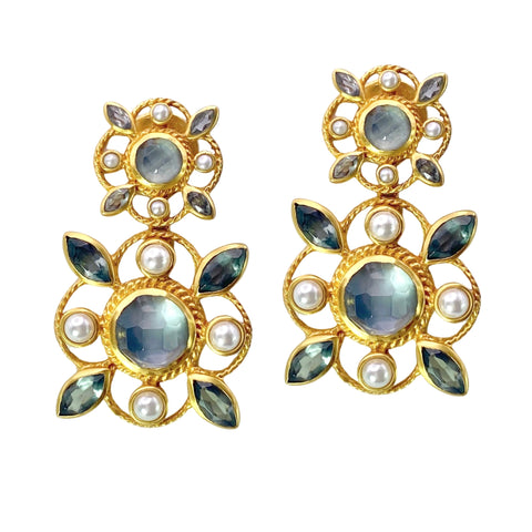 Julie Vos Monaco Statement Earrings  Available at Shaylula Jewlery & Gifts in Tarrytown, NY and online. Julie Vos distilled the opulence of Monaco—the French Riviera’s most lavish locale—into these dangling head-turners. Golden twisted wire quatrefoils frame a series of freshwater pearls and gemstones that catch the light and delicately frame the face.  • 24K gold plate, iridescent charcoal blue, mother of pearl doublet, pearl  • 1.7" L